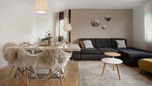 Una sala de estar moderna con una mesa de comedor, sofá y decoración en la pared.