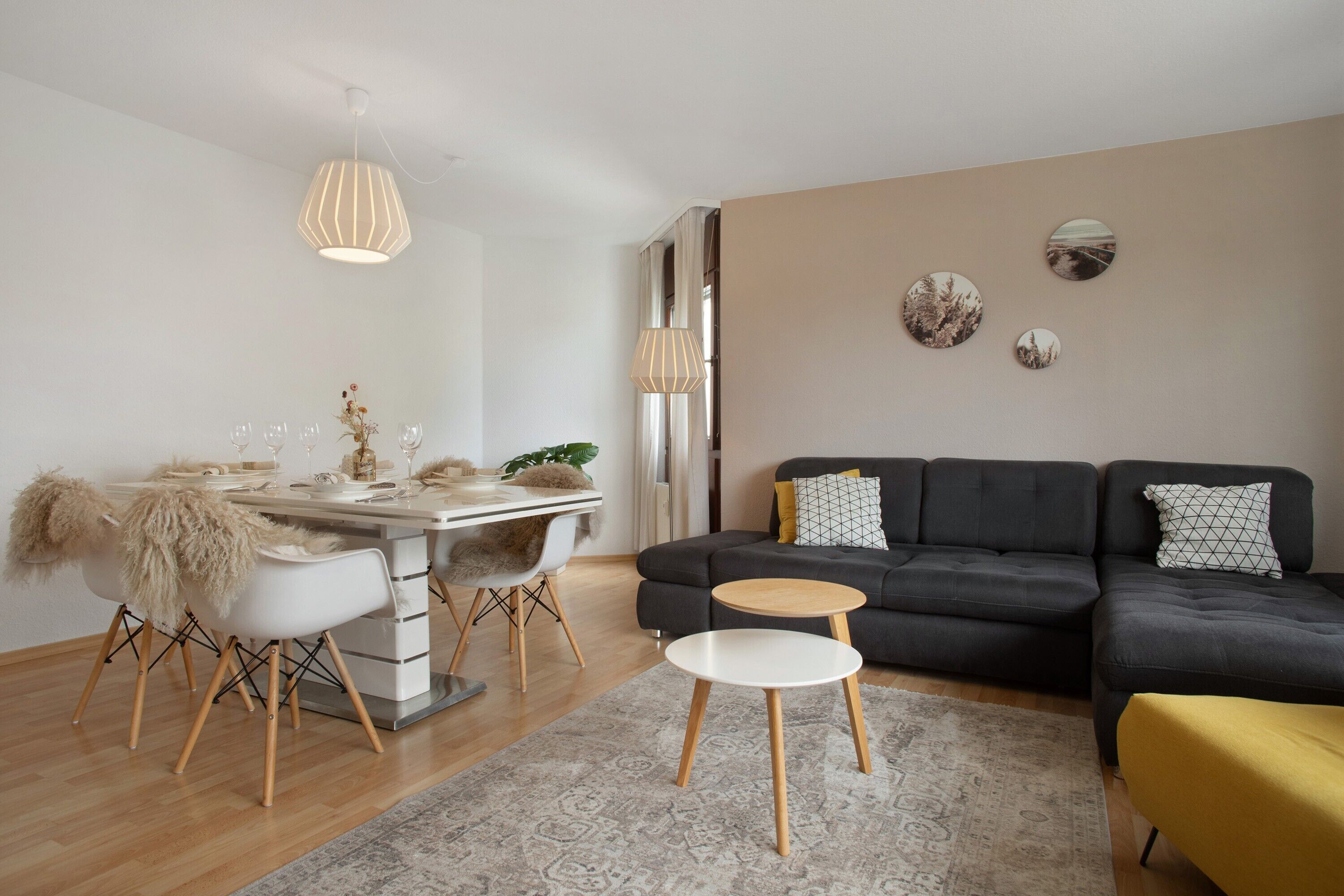 Una sala de estar moderna con comedor, un sofá, una mesa redonda de centro y arte decorativo en la pared.