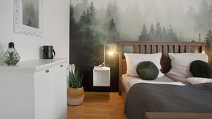 Un dormitorio con cama, mesita de noche, lámpara y una pared decorada con un mural de un bosque.