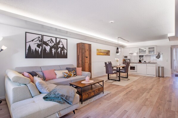 A modern living room with a sofa, coffee table, and artwork on the wall. - Apartment 'Fewo Buddy' with Mountain View, Balcony and Wi-Fi (Todtmoos)
