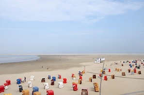 A beach with numerous numbered beach huts and a lifeguard tower.