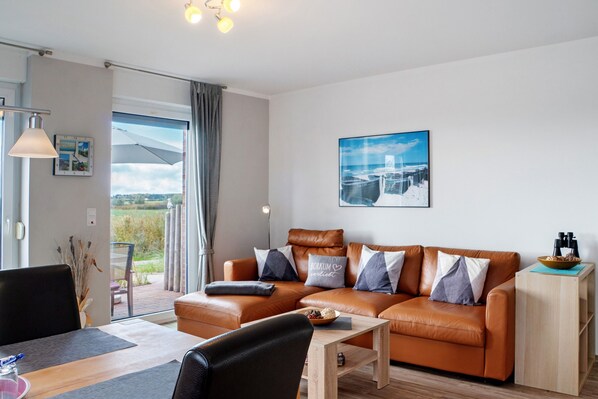 A modern living room with a leather sofa, a wooden coffee table, and a dining area with a table and chairs.