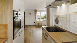 A modern kitchen with a built-in oven, a stovetop, and a window overlooking a garden.