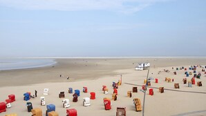 A beach with numerous numbered beach huts and a lifeguard tower.