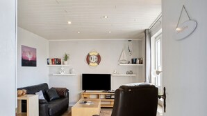 A modern living room with a black leather sofa, a wooden coffee table, a flat-screen TV, and a bookshelf. - Apartment 'Sanddorn' with Wi-Fi (Borkum)
