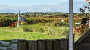 A rural landscape with a stone tower, a wooden fence, and a chair. - Apartment 'Sanddorn' with Wi-Fi (Borkum)