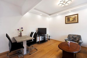 A modern living room with a dining table, chairs, a TV, and a round coffee table.