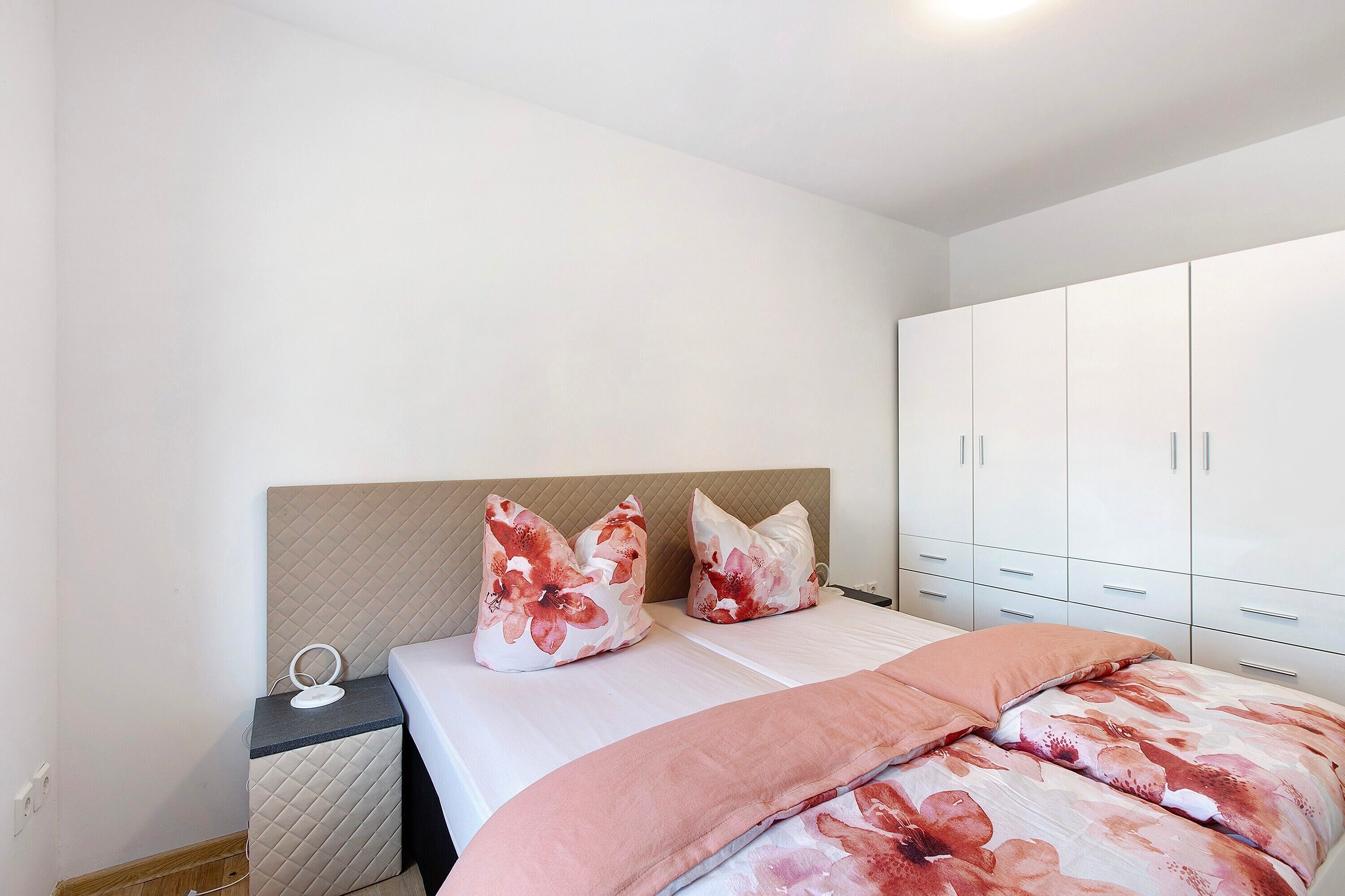Une chambre à coucher avec un lit, deux oreillers, une table de chevet et une armoire.
