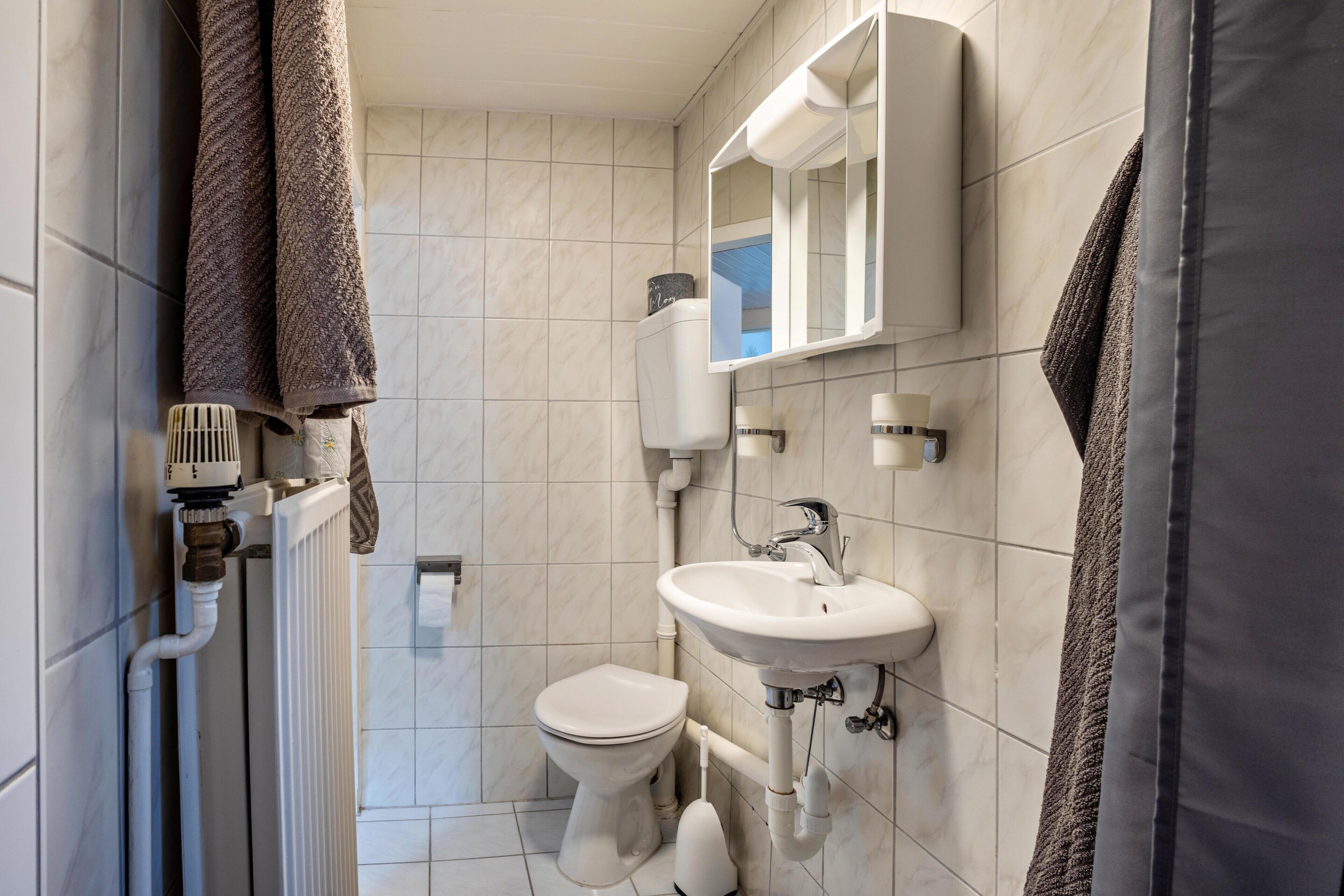 A bathroom with a toilet, sink, and towel rack.