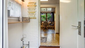 Un pasillo con un letrero de madera, una puerta y vistas a un comedor con sillas y una mesa.