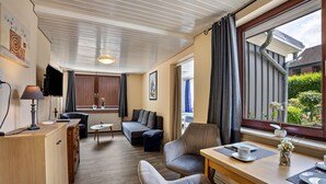 Un espacio habitable compacto con sofá, una mesa de comedor, televisor y una ventana con cortinas.
