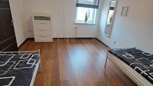 Makuuhuoneessa on kaksi sänkyä, lipasto, patteri, ikkuna, josta on näkymä, ja peili seinällä.