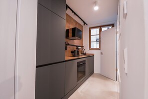 A modern kitchen with dark cabinetry, a wooden countertop, and a built-in oven.