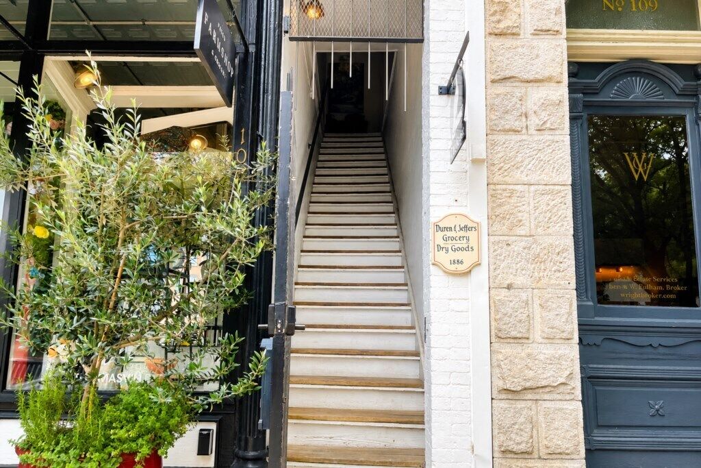 Una escalera que conduce a un edificio con un letrero que indica 'Duren & Jeffers Grocery Dry Goods 1886'.
