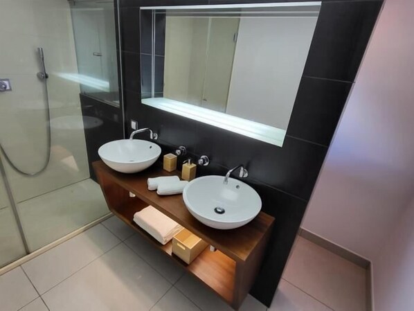 Ein modernes Badezimmer mit zwei weißen Aufsatzwaschbecken, einem großen Spiegel und einer Holzkommode.