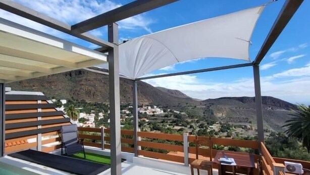 A modern outdoor terrace with a pool, wooden furniture, and a view of a mountainous landscape. - Natural beauty at Sol Caldera de Temisas (Temisas)