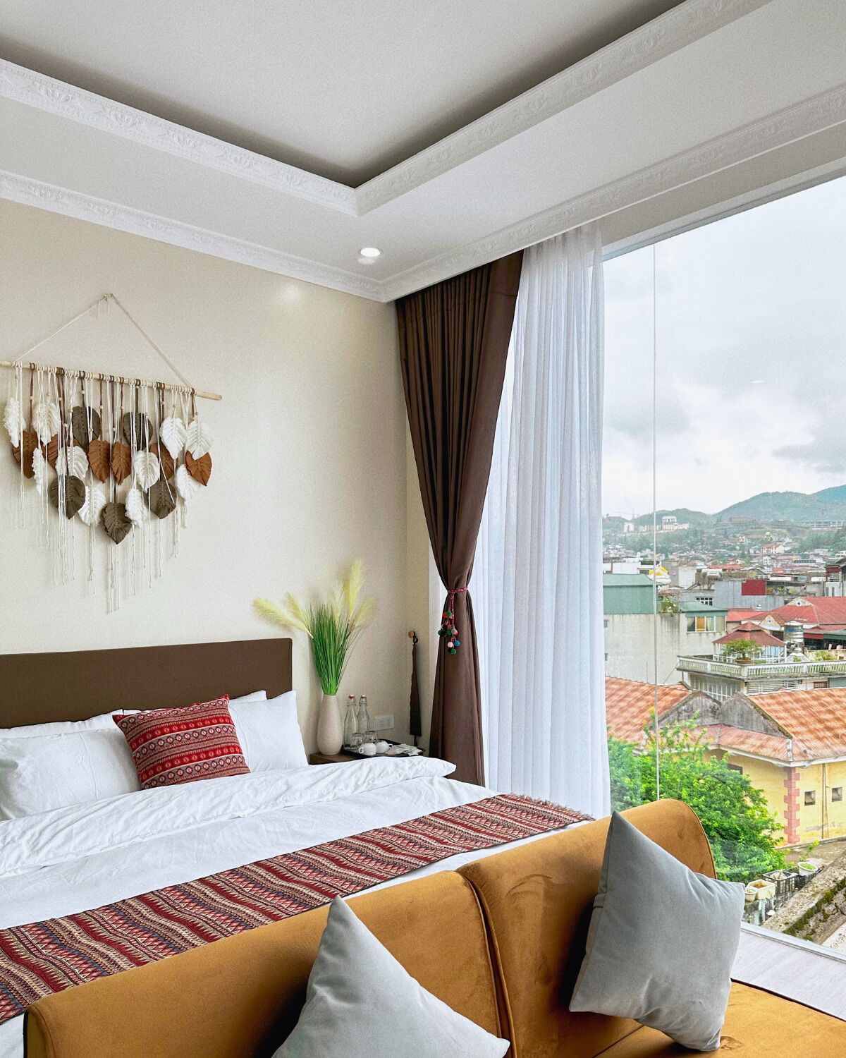 Habitación de hotel con cama, sofá, vistas de la ciudad y un tapiz decorativo.