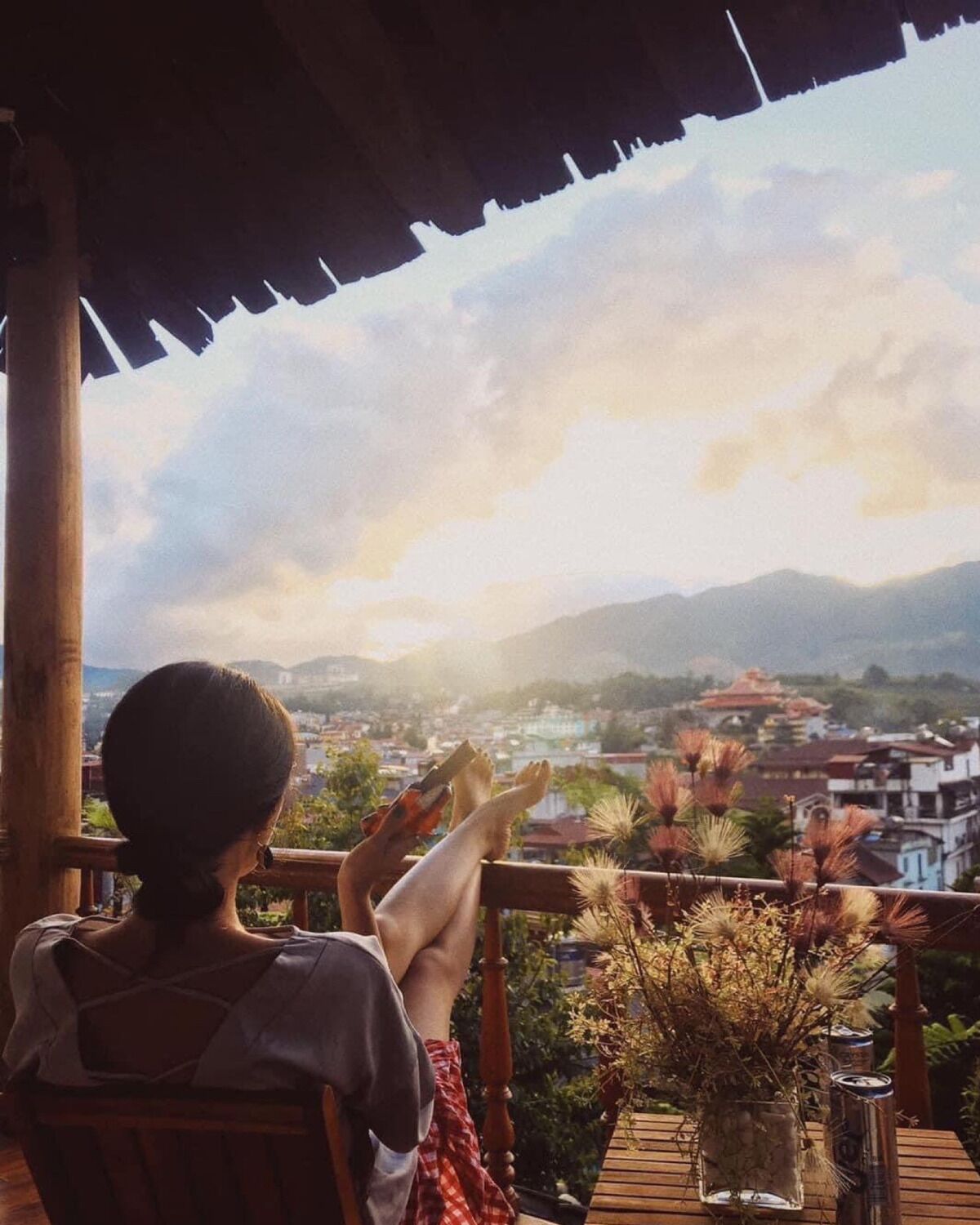 A person sitting on a wooden deck overlooking a cityscape with mountains in the distance.