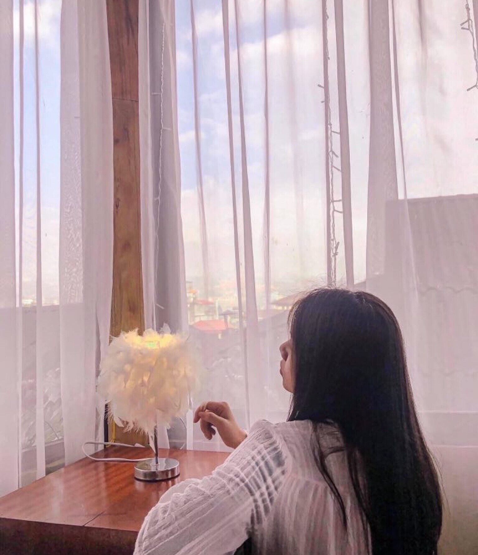 A room with a large window, a wooden table, and a white chair.