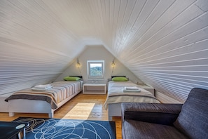 A small, cozy attic bedroom with two beds, a window, and a view of the outdoors. - Haven Near The River (Duga Resa)