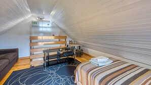 A compact, well-lit attic bedroom with a sloped ceiling, a wooden bed, a small desk, and a couch. - Haven Near The River (Duga Resa)