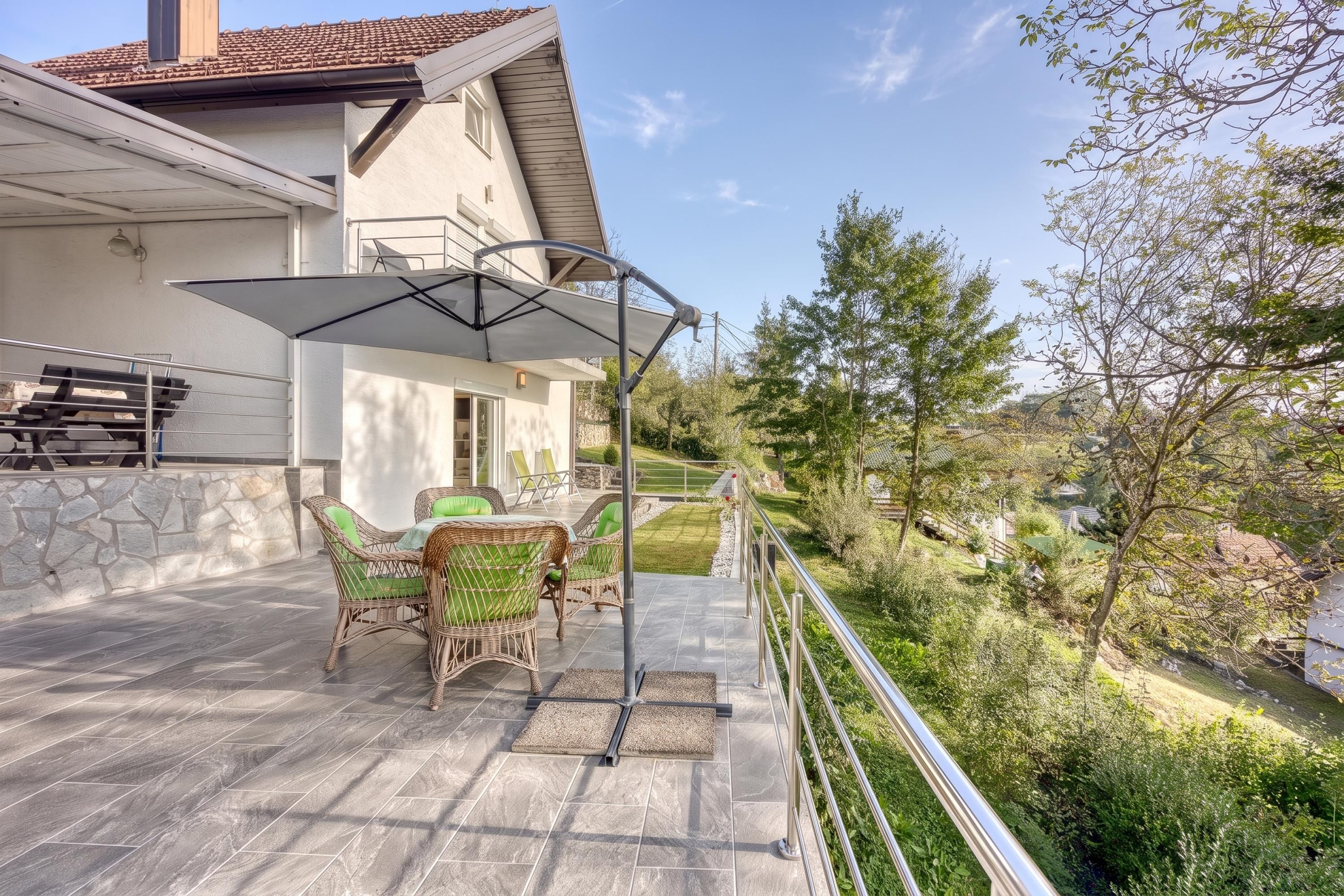 A patio with outdoor furniture, a covered area, and a view of the surrounding landscape.