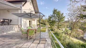 A patio with outdoor furniture, a covered area, and a view of the surrounding landscape.