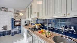 A kitchen with white cabinets, a blue backsplash, a wooden countertop, and a sink. - Haven Near The River (Duga Resa)