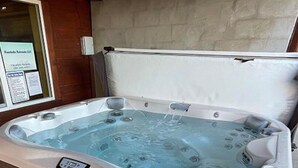 Een bubbelbad met bedieningspaneel, een raam met een bordje en een bakstenen muur op de achtergrond.
