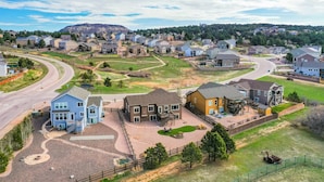 A residential area with houses, a winding road, and a hilly landscape in the background. - Mountain Breeze! Fire Pit, Air Hockey & Views! (Monument)