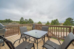A deck with a table and chairs, overlooking a grassy area and trees. - Mountain Breeze! Fire Pit, Air Hockey & Views! (Monument)