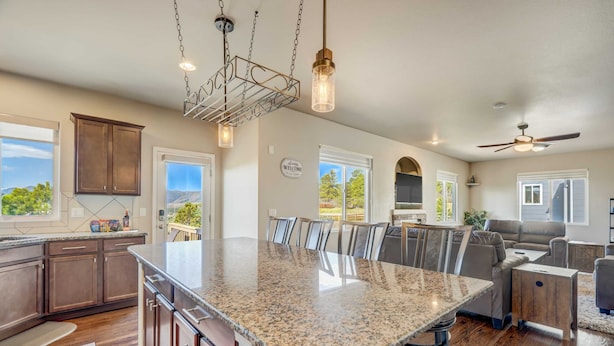 A spacious kitchen with granite countertops, dark wooden cabinets, and a large island. - Mountain Breeze! Fire Pit, Air Hockey & Views! (Monument)
