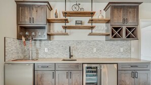 A modern kitchen with wooden cabinets, stainless steel appliances, and a marble backsplash. - Mountain Breeze! Fire Pit, Air Hockey & Views! (Monument)