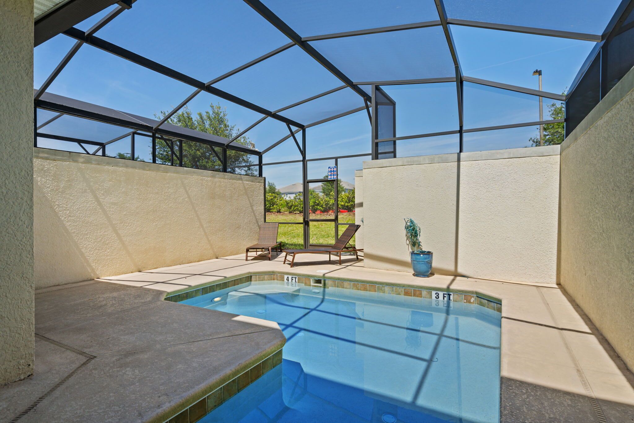 Una piscina al aire libre techada con sillones de descanso y una planta en maceta.