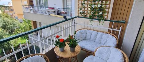 A balcony with wicker furniture and potted plants.