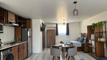 Un espacio habitable compacto con kitchenette, comedor y cama.