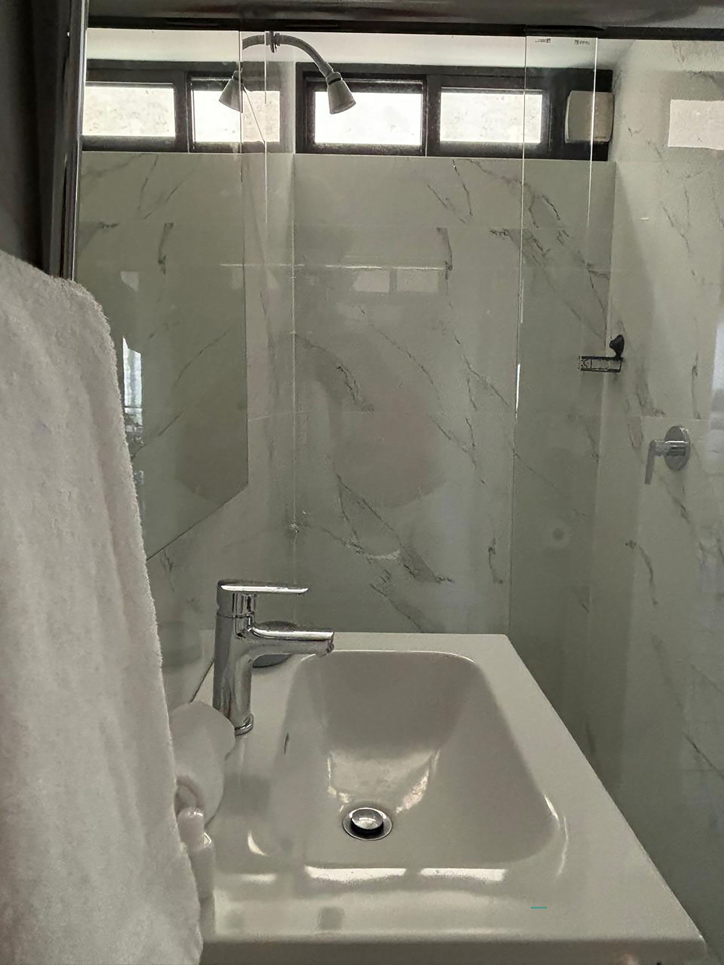A bathroom with a shower, a sink, and a towel rack.