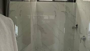 A bathroom with a shower, a sink, and a towel rack.