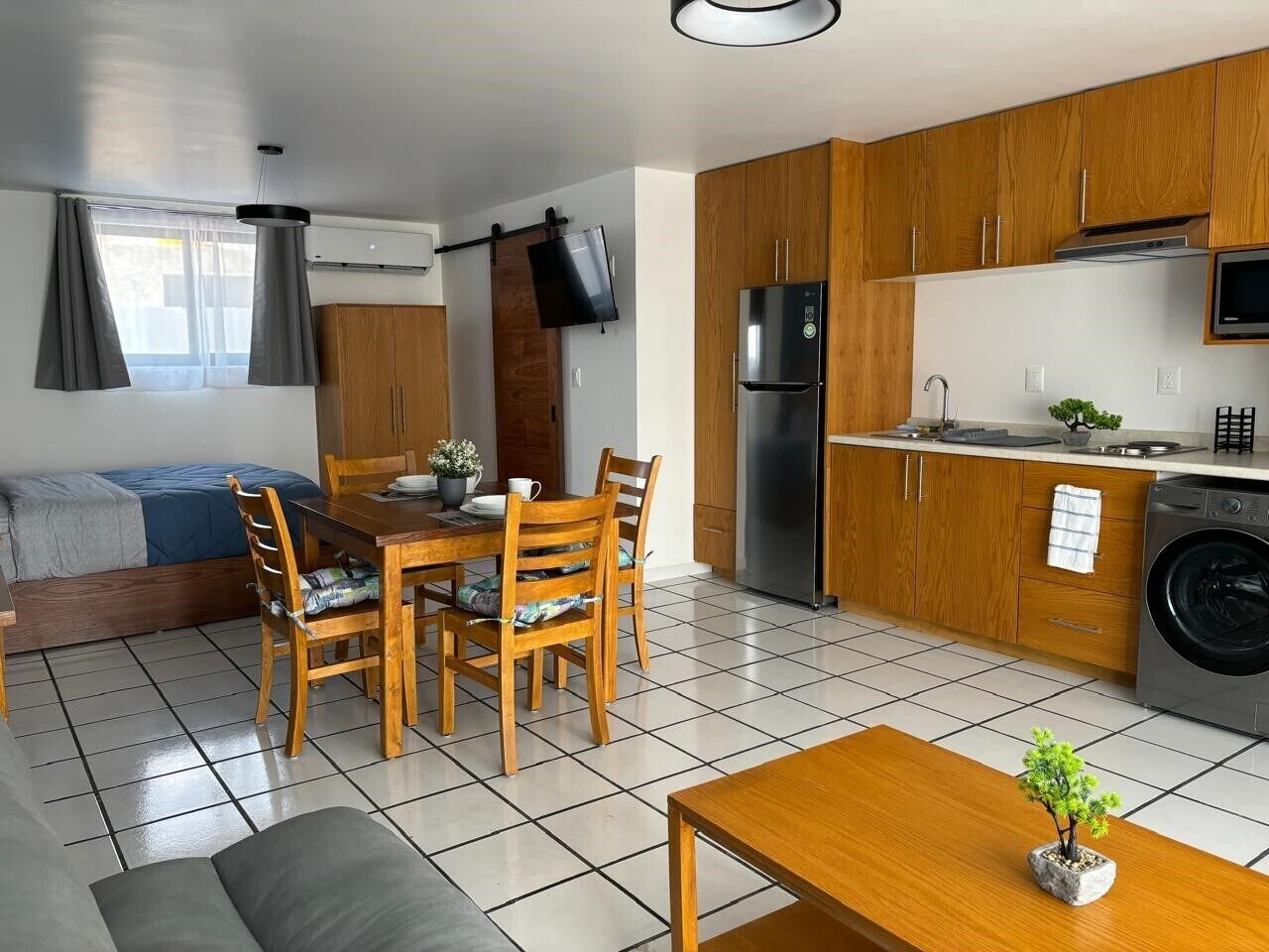 A compact living space with a dining area, kitchenette, and a sofa bed.