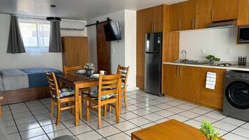 A compact living space with a dining area, kitchenette, and a sofa bed.