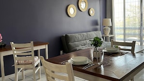 A dining area with a dark wall, a grey sofa, and three wall-mounted mirrors.
