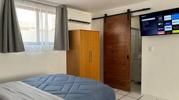 Ein Schlafzimmer mit Bett, Kleiderschrank, Schiebetür, Fernseher und Deckenleuchte.