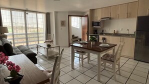 A modern kitchen with a refrigerator, microwave, and sink. There is a dining area with a table and chairs.
