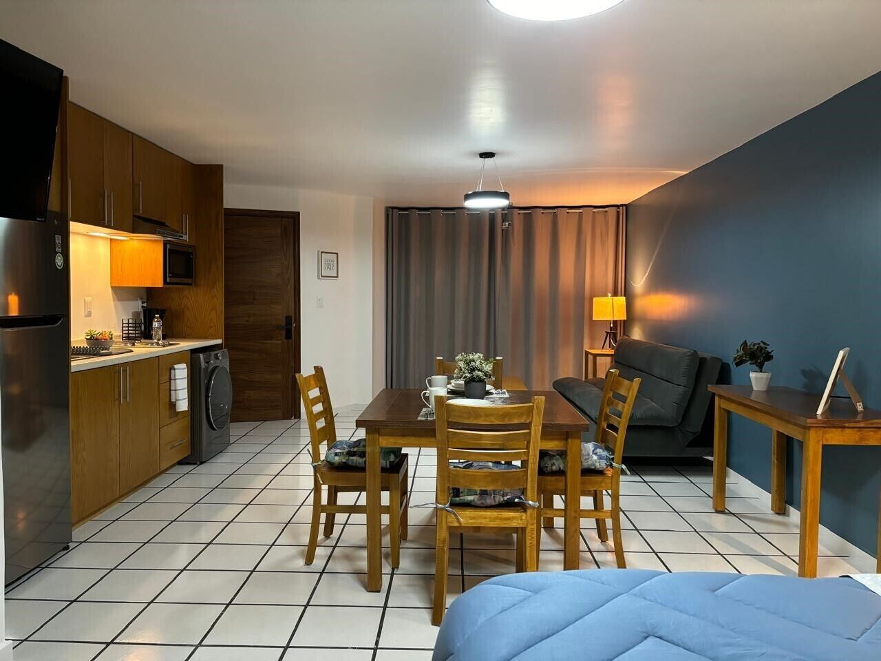 Espaço compacto com cozinha americana, área de refeições e cama.