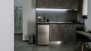 A compact kitchen with stainless steel appliances, a sink, and a small dining area. - Crystal Studios (Aristotelis)