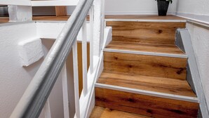 Una escalera de madera con barandas blancas y una orquídea en maceta.