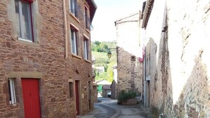 Una calle estrecha con edificios de piedra, puertas rojas y cielo despejado.