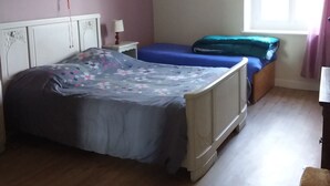 Un dormitorio con una cama, una mesita de noche, una lámpara, una ventana y una silla.