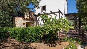 A garden with a pergola, a stone wall, and a white building with a window. - Villa Olivia - a compund villa witha  private pool (Douliana)