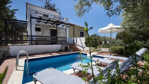 A pool area with a clear blue pool, lounge chairs, and a building with a pergola. - Villa Olivia - a compund villa witha  private pool (Douliana)